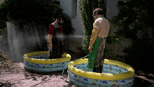 a man wearing a gas mask is spraying another man in a pool
