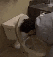 a man is drinking out of a toilet .