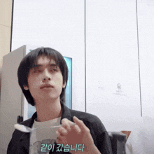 a man in a black jacket holds a spoon in his hand with korean writing on the bottom