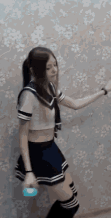 a girl in a sailor outfit is dancing with a blue object