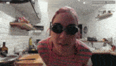 a woman wearing goggles in a kitchen with the number 44 on the wall behind her