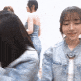 a woman in a denim jacket is standing next to a woman in a strapless top