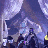 a group of people are taking pictures of a performer on their phones