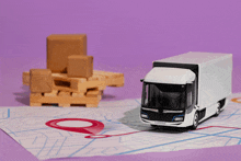 a toy truck sits on a map next to a stack of wooden pallets