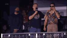 three men are standing in front of a sign that says " live "
