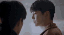 a man in a brown coat is looking at a woman in a white shirt