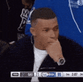 a man wearing a watch is watching a basketball game between the sas and bkn teams