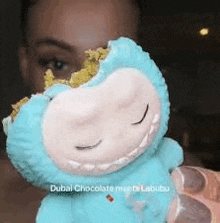 a woman is holding a stuffed animal with a bite taken out of it and a cookie in its mouth .