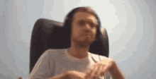 a man is sitting in a chair wearing headphones and making a funny face .