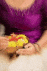 a woman in a purple shirt is holding a sandwich in her hands