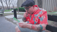 a man sits on a bench smoking a cigarette and looking at his phone