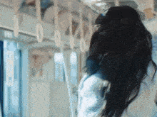a woman with long dark hair is riding a train