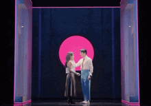 a man and a woman are dancing in front of a pink circle .