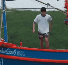 a man in a white shirt and shorts is walking on a boat .