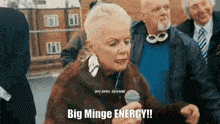 a woman is holding a microphone and says big minge energy