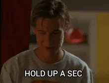 a young man says hold up a sec in a white shirt