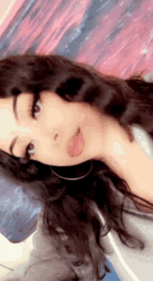 a woman with long hair and hoop earrings is laying on a bed .