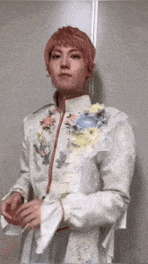 a man with red hair is wearing a white dress with flowers on the sleeves