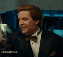 a man in a tuxedo with a bow tie is talking to a woman .