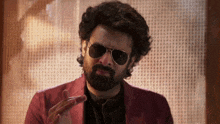 a man with a beard is wearing sunglasses and a red suit