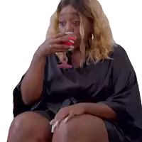 a woman in a black robe is drinking from a glass .