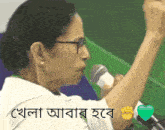 a woman speaking into a microphone with a fist in the air and a heart in the corner