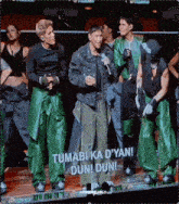 a group of men are standing in front of a screen that says " tumabi ka d'yan "