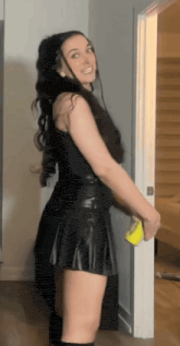 a woman in a black dress is standing in a doorway holding a yellow object