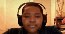 a young boy is wearing headphones and looking at the camera .