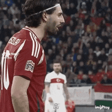 a soccer player wearing a headband is standing in front of a crowd on a soccer field .