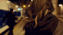 a woman 's hair is blowing in the wind at a train station