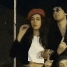 a woman wearing a red beret is standing next to a man wearing sunglasses .