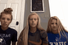 three girls are standing next to each other in front of a chalkboard that says " i am "