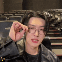 a man wearing glasses and a leather jacket is sitting in a theater