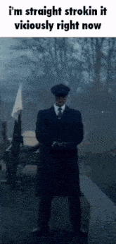 a man in a suit and tie is standing in front of a cannon and trees .
