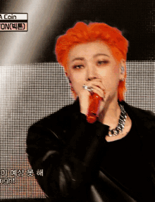 a man with red hair is singing into a red microphone with a coin on the bottom right