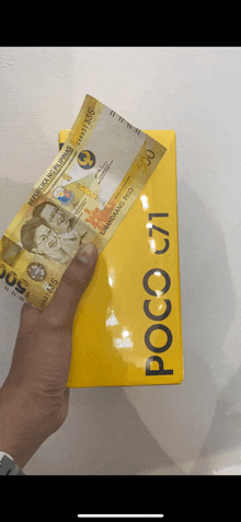 a person is holding a 500 peso bill in front of a poco c1 phone