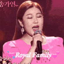 a woman in a pink dress is singing into a microphone with the words royal family written on the bottom