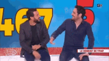 two men are sitting next to each other in front of a sign that says cb .