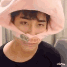 a man wearing a pink hat with a dollar bill on his mouth .