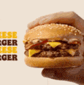 a person is holding a cheeseburger in their hand in front of a sign that says cheeseburger