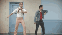 two men are dancing in front of a door labeled kitchen
