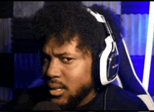 a man with a beard is wearing headphones and making a face