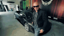 a man wearing sunglasses stands in front of a car with a sign behind him that says ephyr
