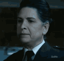 a woman in a suit and tie is looking at the camera .