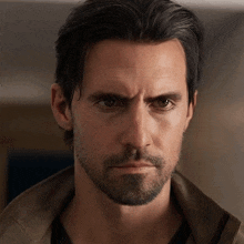 a man with a beard and long hair looks at the camera