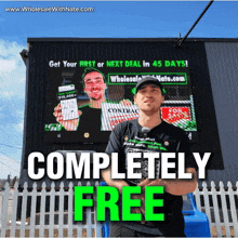 a man is standing in front of a large screen that says completely free