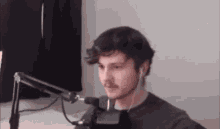 a man is sitting in front of a microphone .