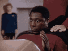 a man with a surprised look on his face is sitting in front of a laptop .