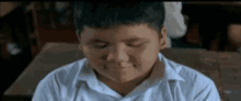 a young boy is sitting at a desk in a classroom .